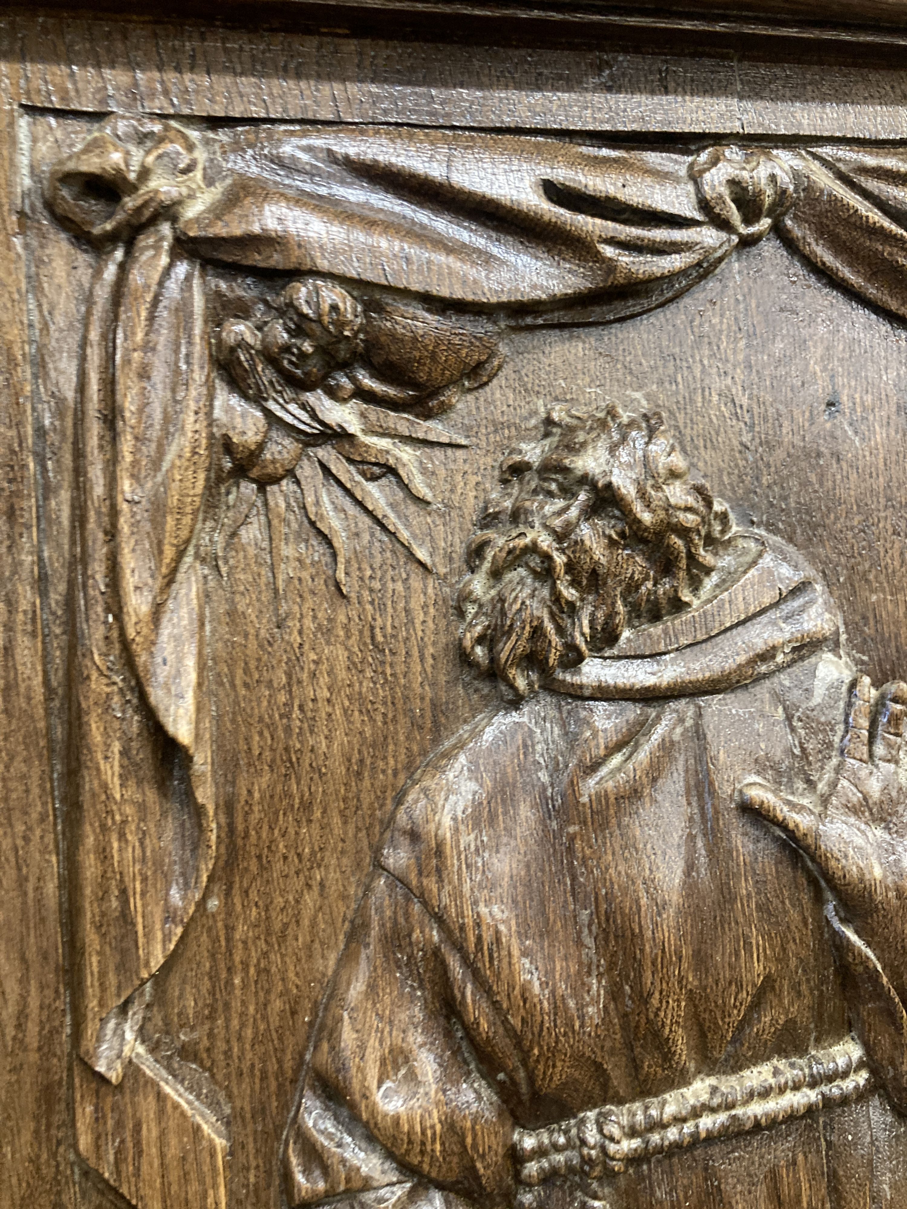 A rectangular carved oak wall panel depicting religious scene